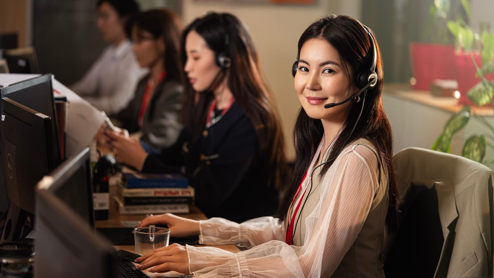 Klantenservicemedewerker met headset helpt vriendelijk een klant achter de computer