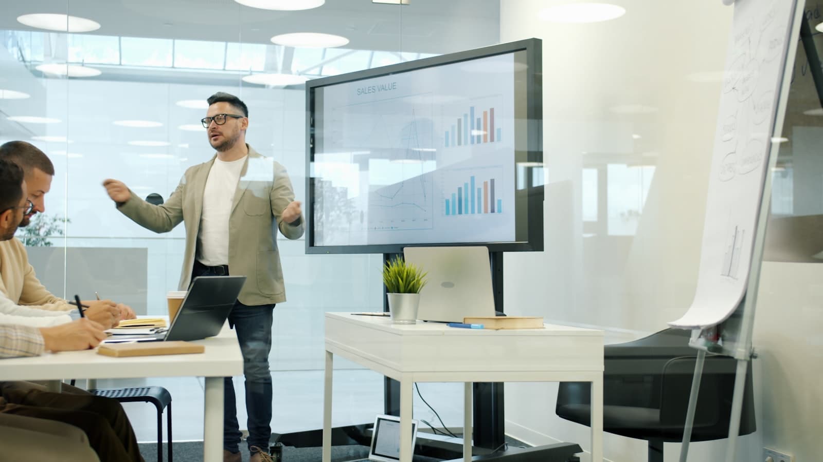 Collega presenteert data en resultaten op een groot scherm aan luisterend team
