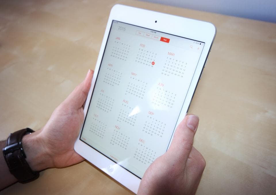 Hand houdt een tablet vast met een planning op het scherm