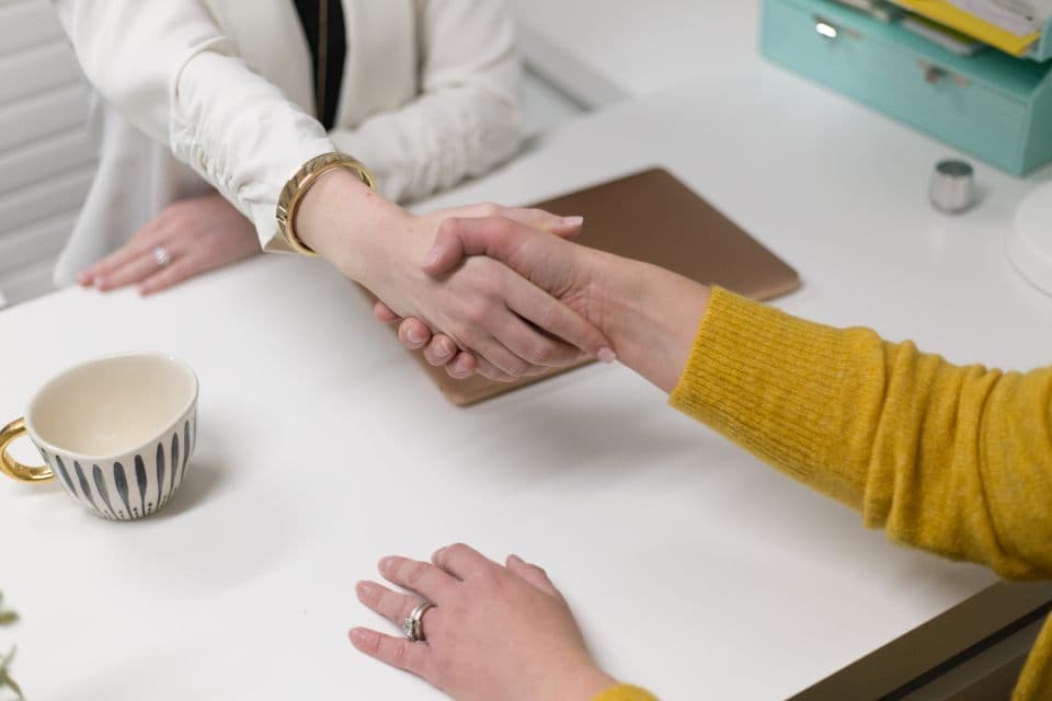 Twee mensen schudden elkaar de hand aan een bureau na een gesprek