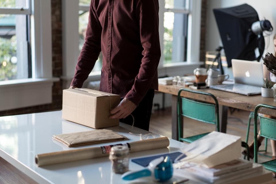 Medewerker pakt een kartonnen doos in aan een werktafel